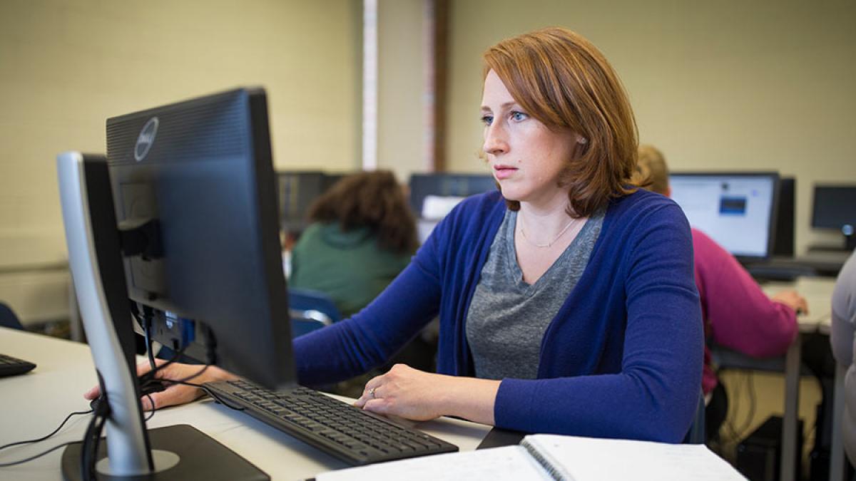 Student sitting at a desk, working on her computer.