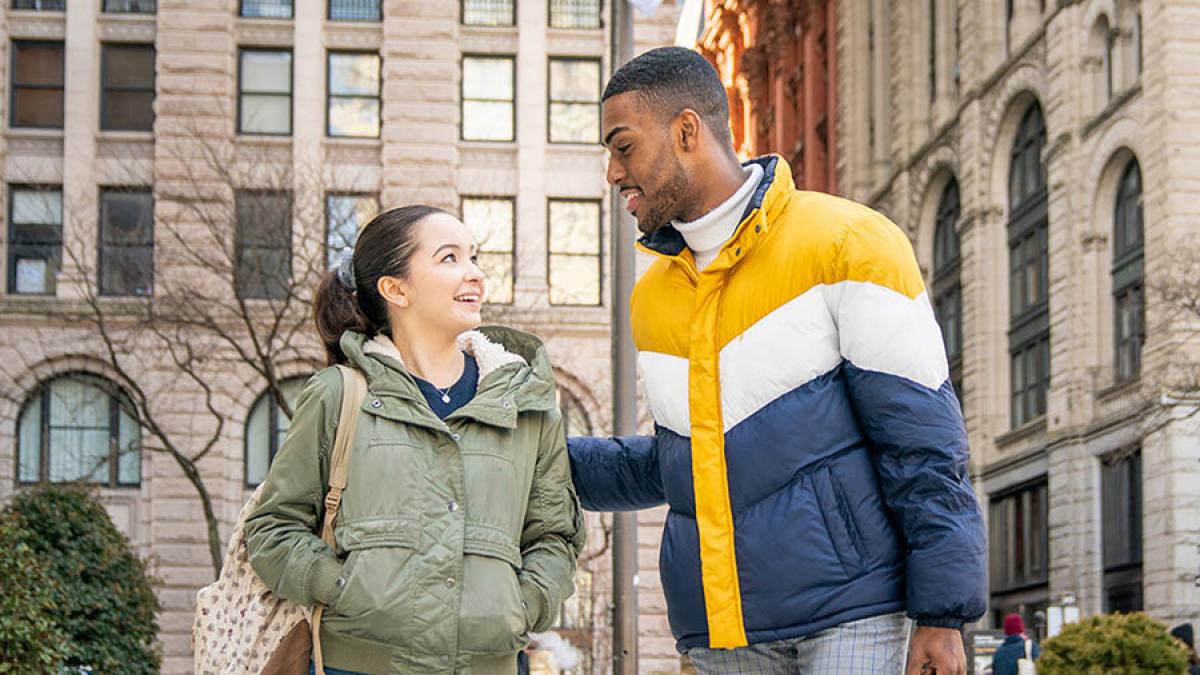 Two Pace students walking in front of 1 Pace Plaza, talking and smiling.