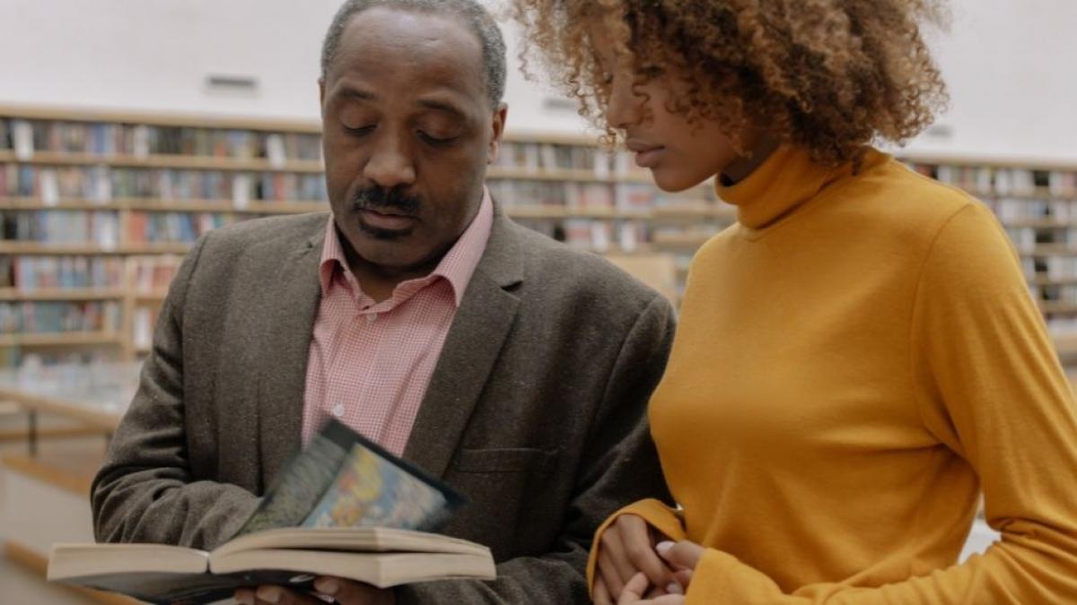 Black professor and student reading a book