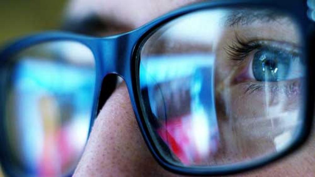 close up of eyeglasses and eye reflecting a computer screen