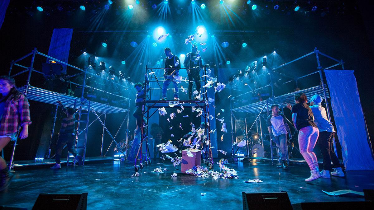 Wide shot of a stage set with blue and purple lighting and scaffolding