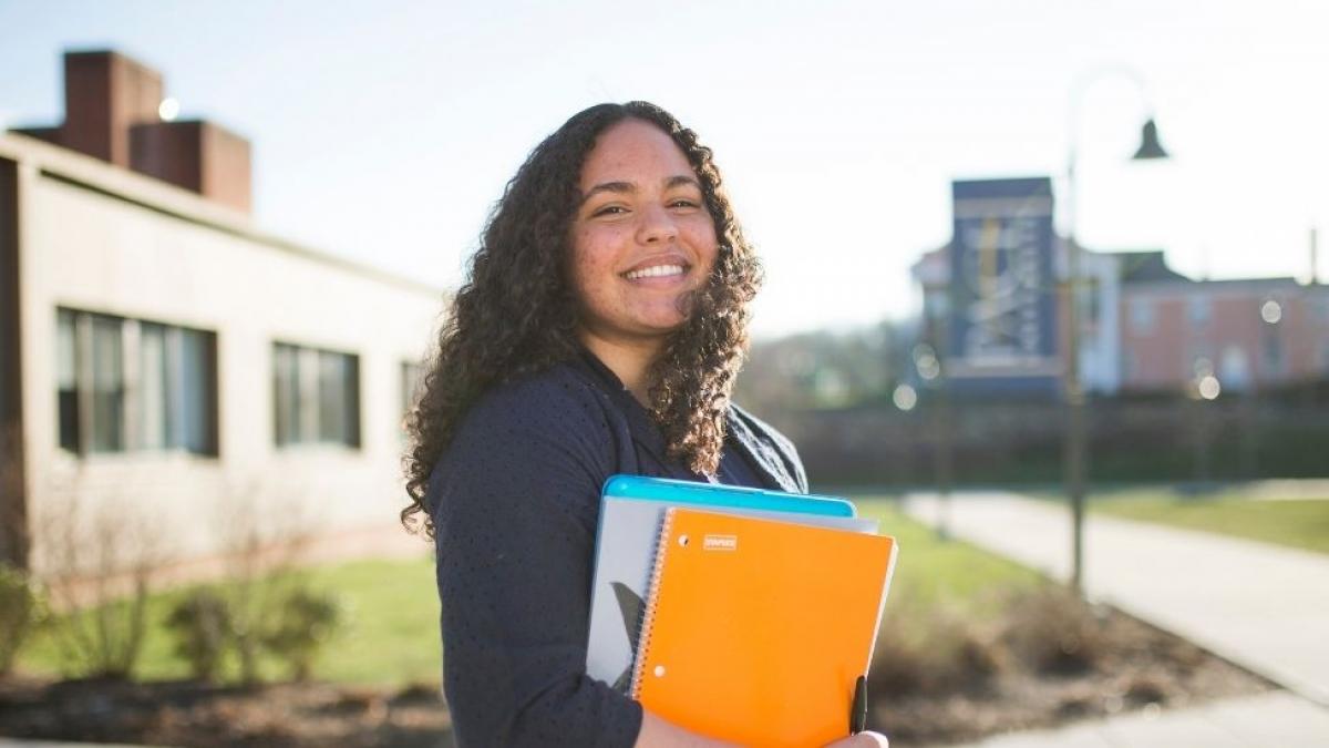 girl smiling on college campus holding books