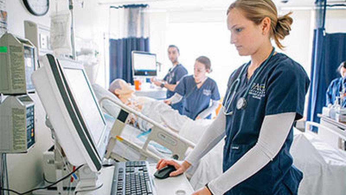 young woman in scrubs at computer at the Pace University Lienhard School of Nursing