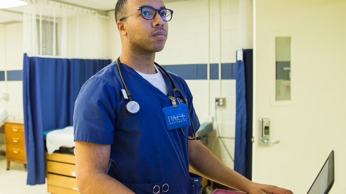 College of Health Professions student working on a computer in a clinical setting.