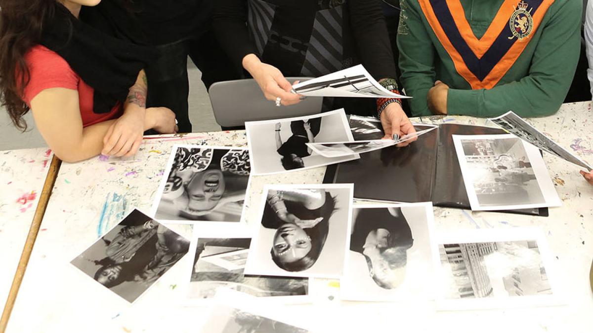 Students reviewing black and white photograph prints on a table