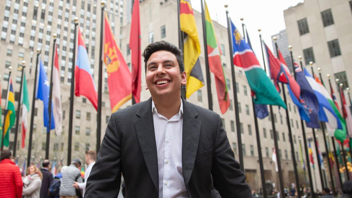 Young man standing in front of a row of world flags in New York City