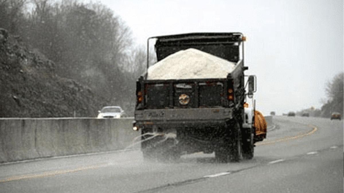 Behind photo of a salt truck distributing salt on a road