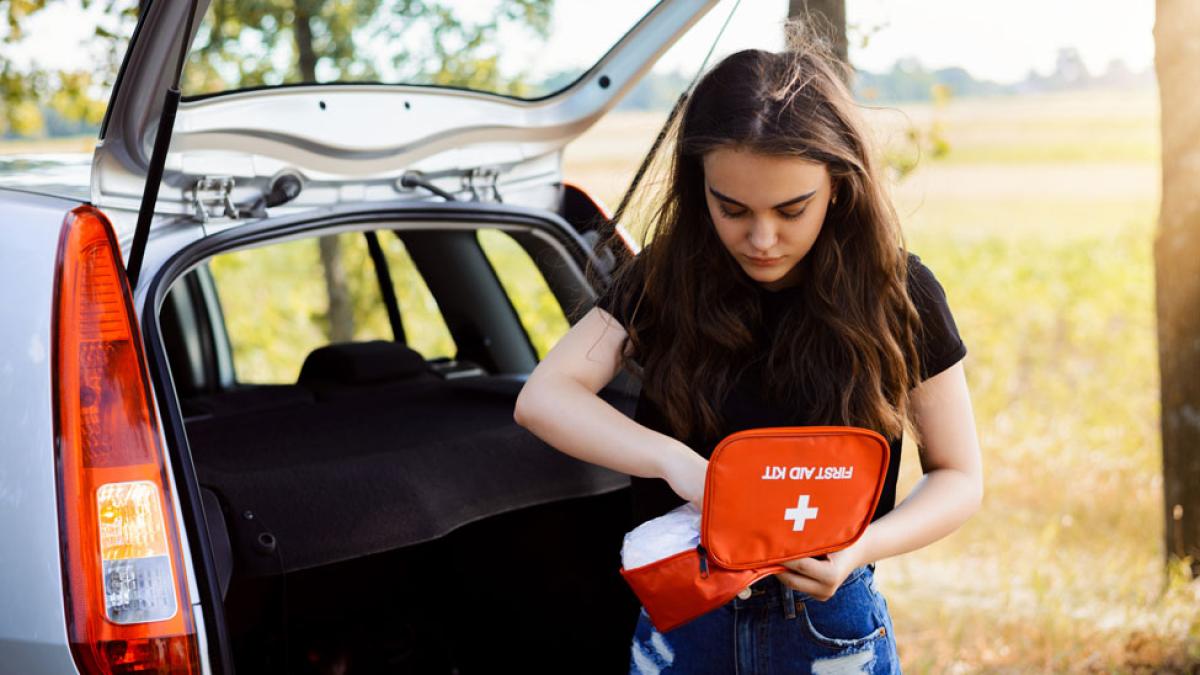 woman with first aid kit near car