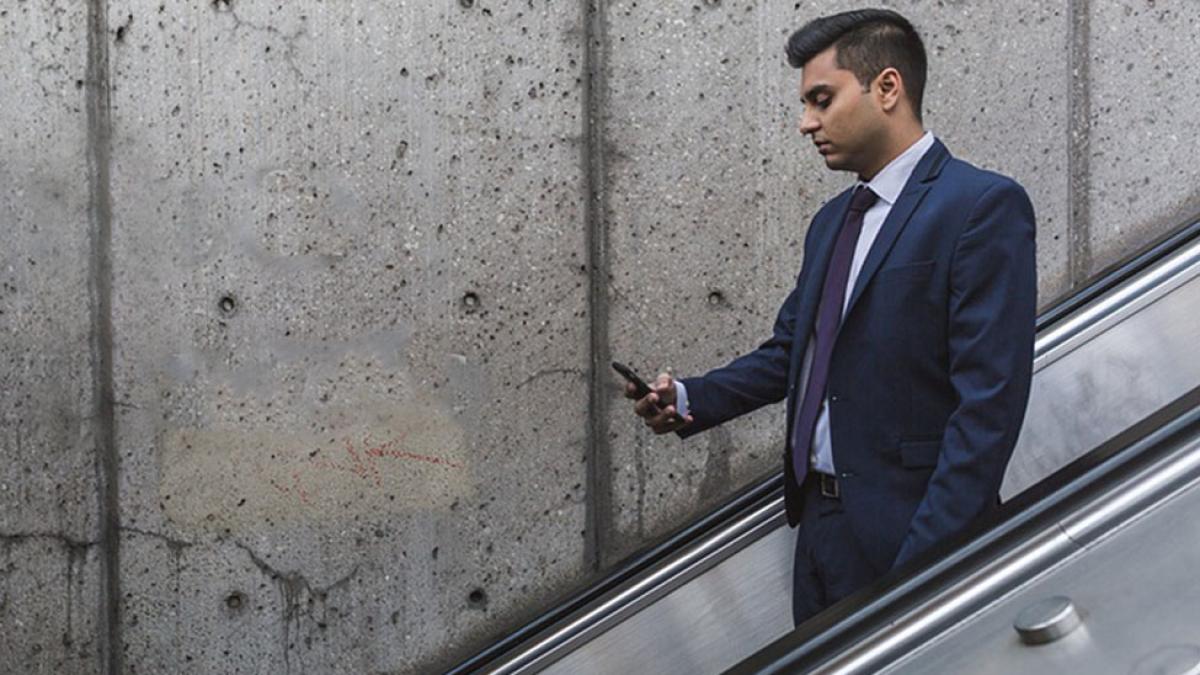 Male student in a suit going down an escalator 