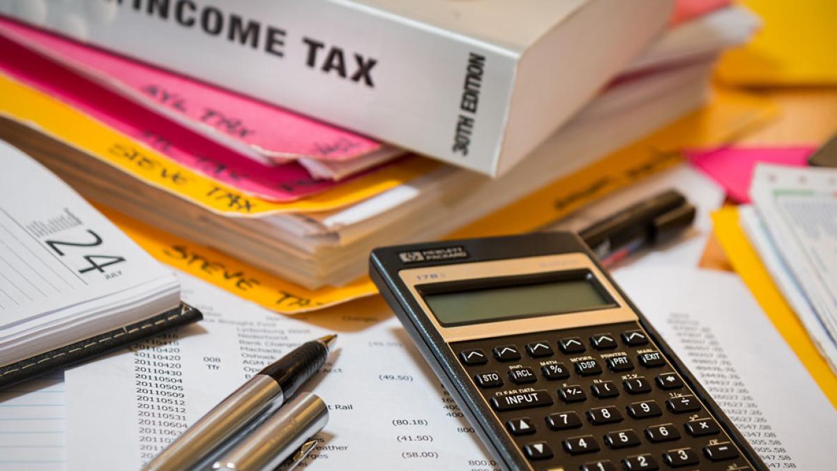 tax code book, pens, and calculator representing taxation