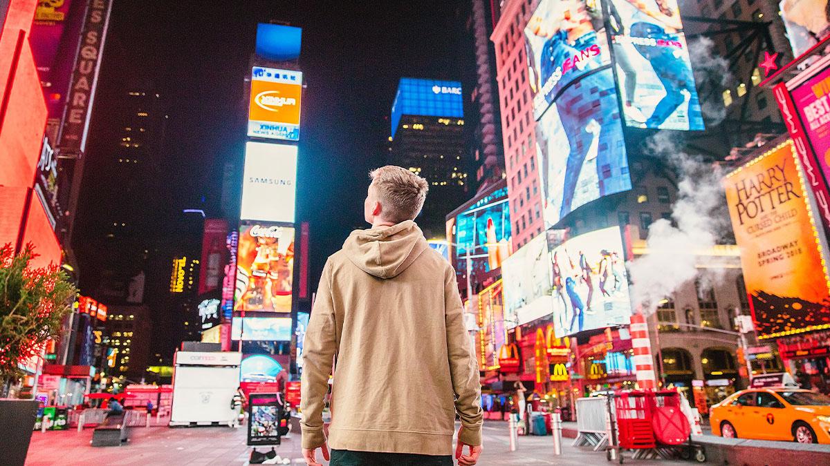 Individual standing in Times Square looking at the advertising and billboards 