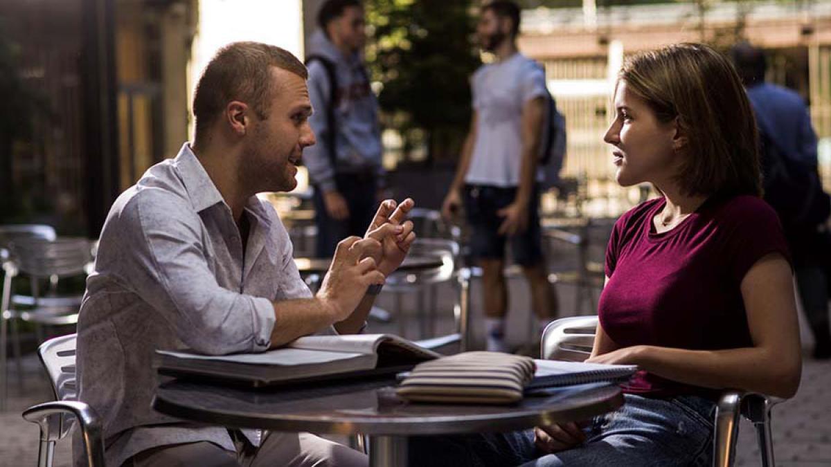 two graduate students talking at table in Bryant Park, NYC