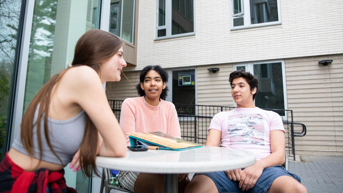 Student sitting at a table outside of Elm Hall in Pleasantville