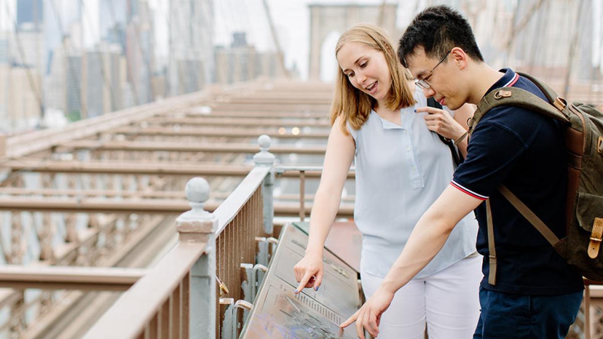 Two pace students reading a plaque on the Brooklyn Bridge.