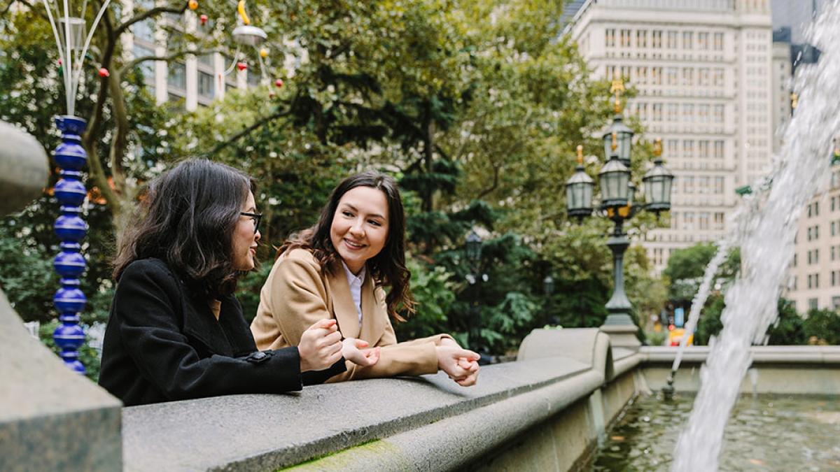 Two pace faculty talking next to fountain