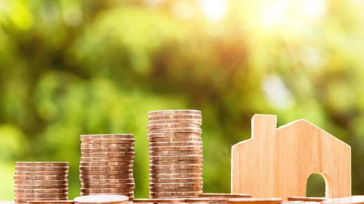 abstract image of stack of coins and tiny wooden house representing the idea of property taxes