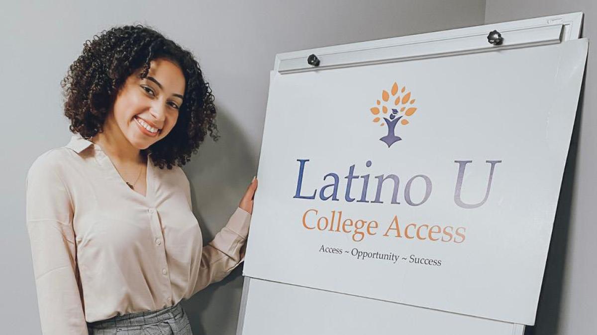 Pace University student in front of a sign that says Latino U