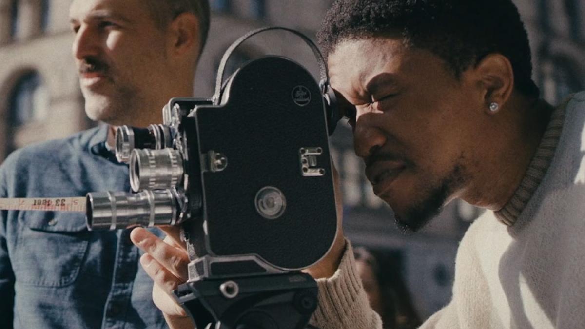 young man looking into the viewfinder of a vintage camera