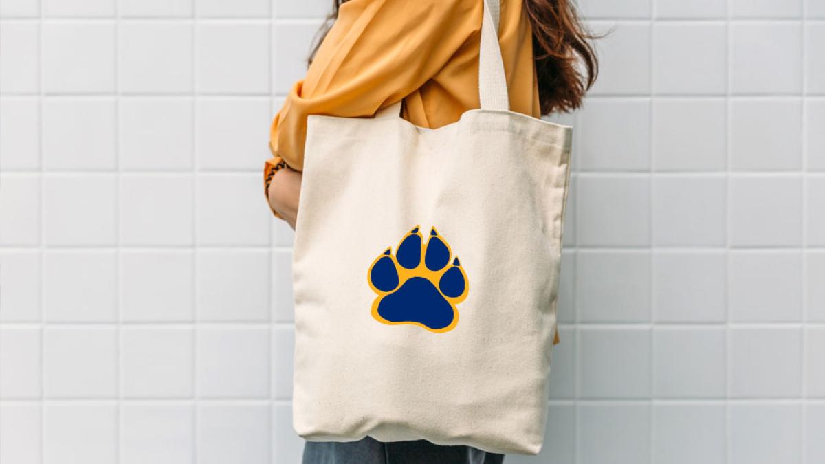 woman holding a canvas tote bag with a pace paw print