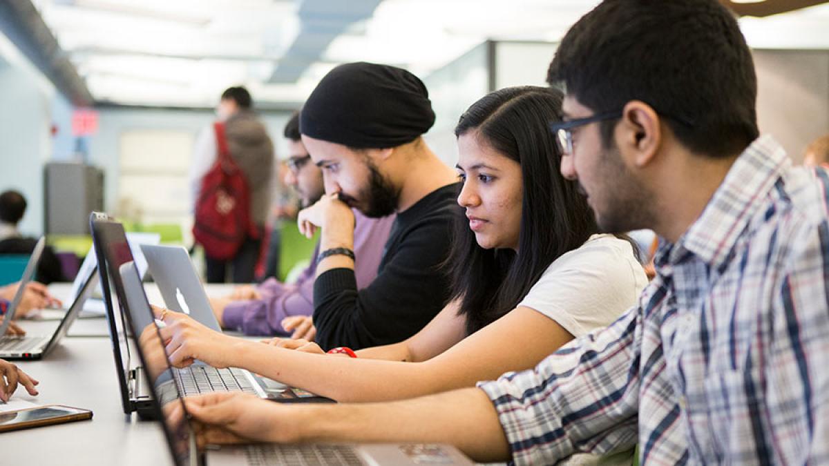 Students sitting in front of computers working on projects together.