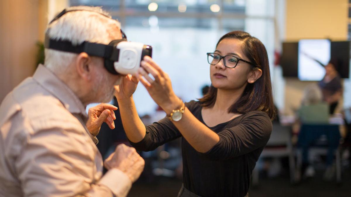 student helping a man with a VR/AR headset