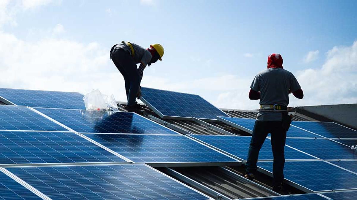 two men installing solar panels on a roof