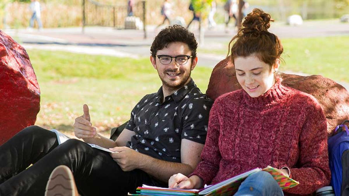 two students studying on campus lawn