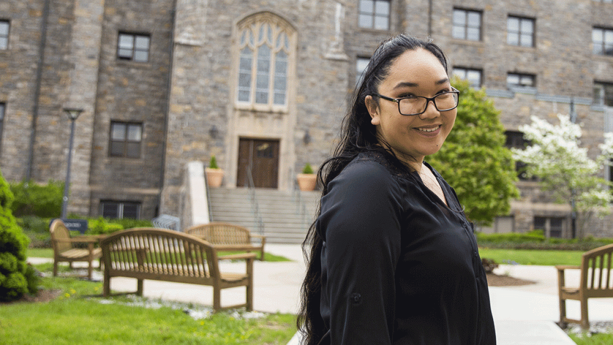 Student standing in front of Aloysia Hall at the Law School campus.