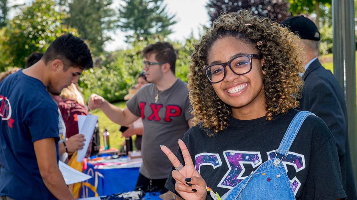 Student smiling at the camera making a peace sign.