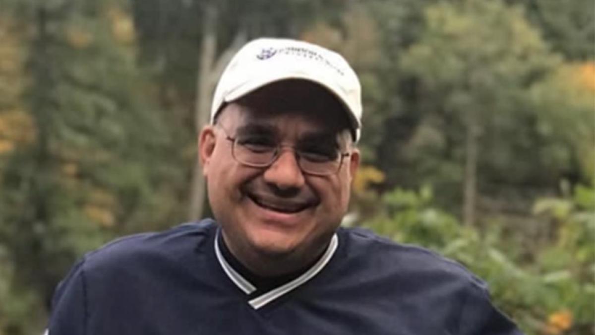 man in baseball cap smiling with trees in background