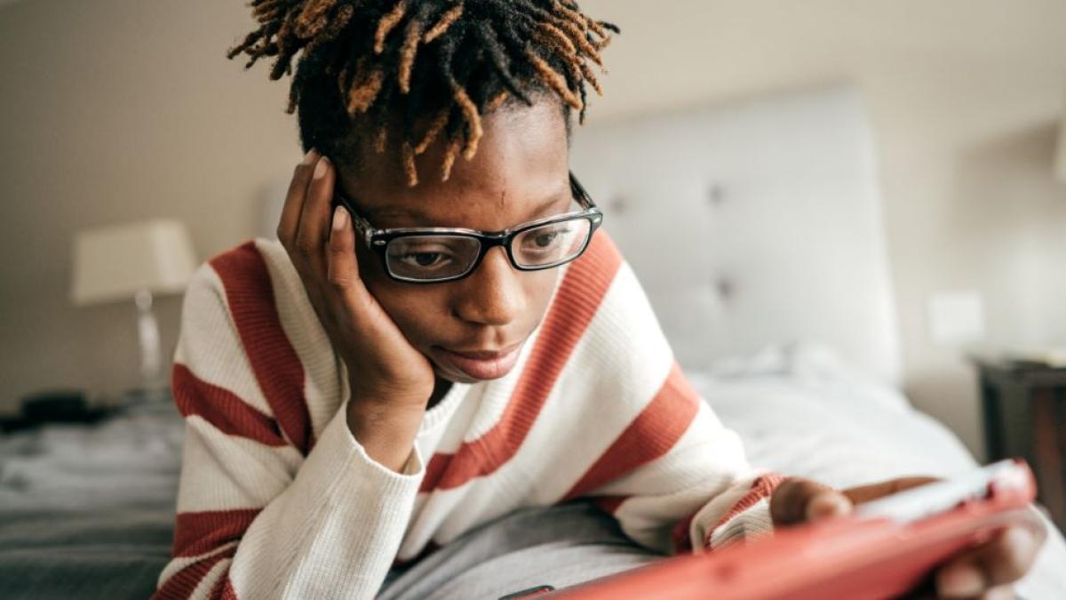 sad boy with glasses looking at his tablet