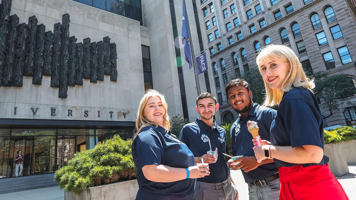 Group of students standing in front of the New York City campus, smiling at the camera.