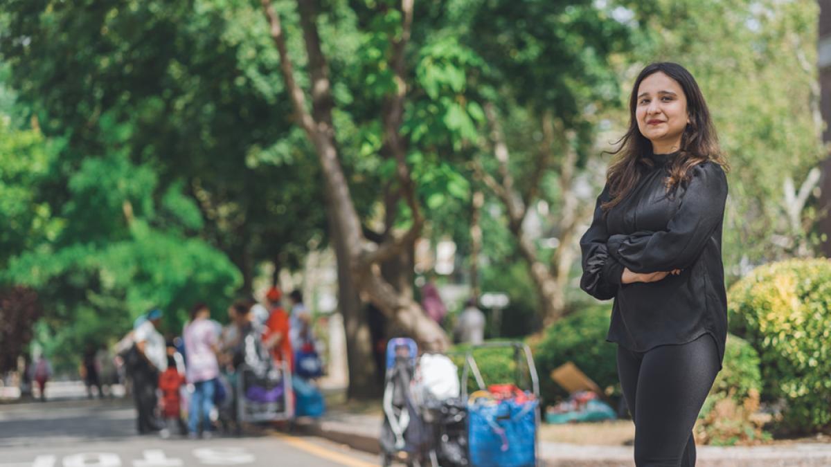 Rashmi Sharma stands with crossed arms and smiles at the camera