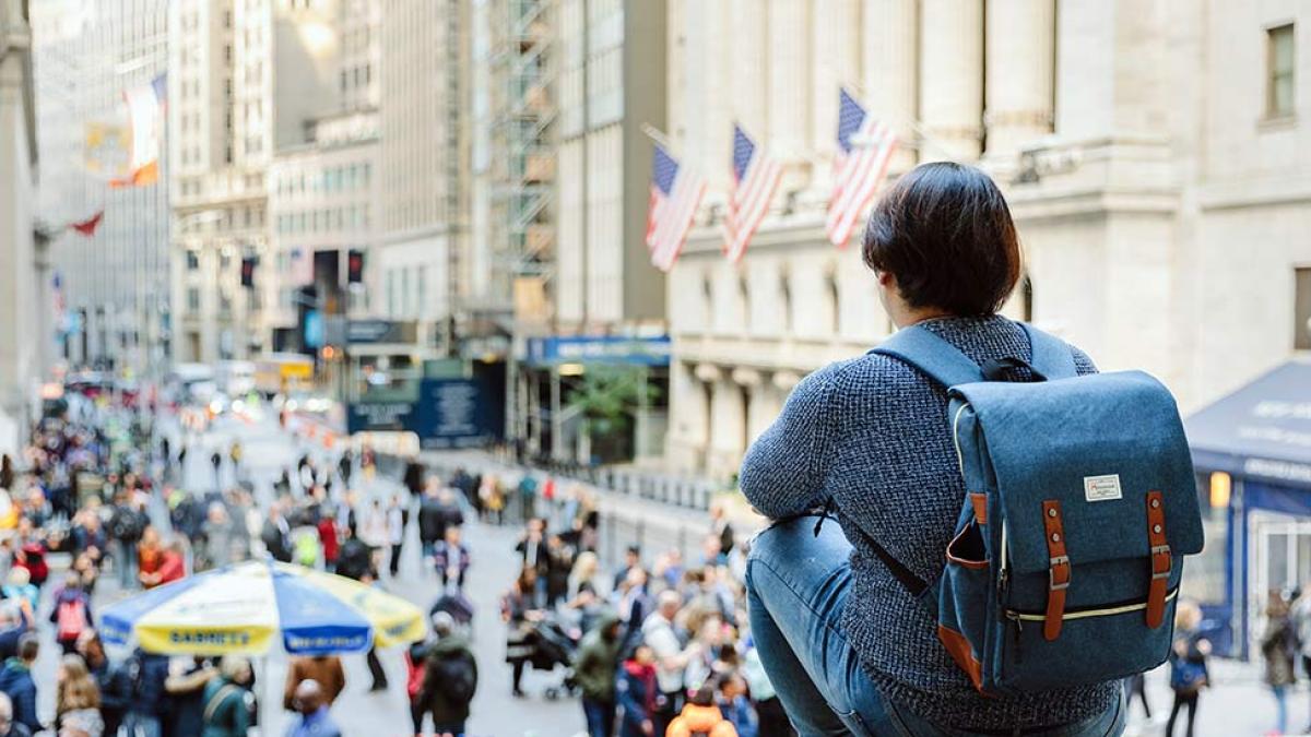 Pace Student sitting on the steps of a building on Wall Street.