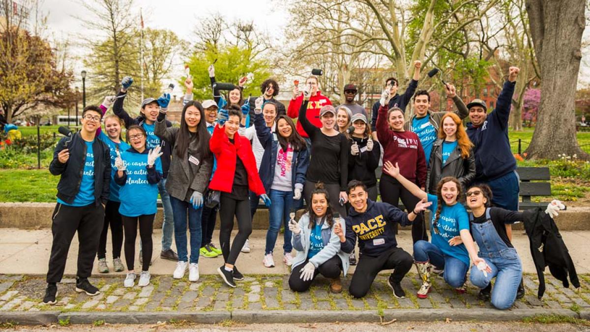 Pace students smile and hold up paintbrushes after volunteering