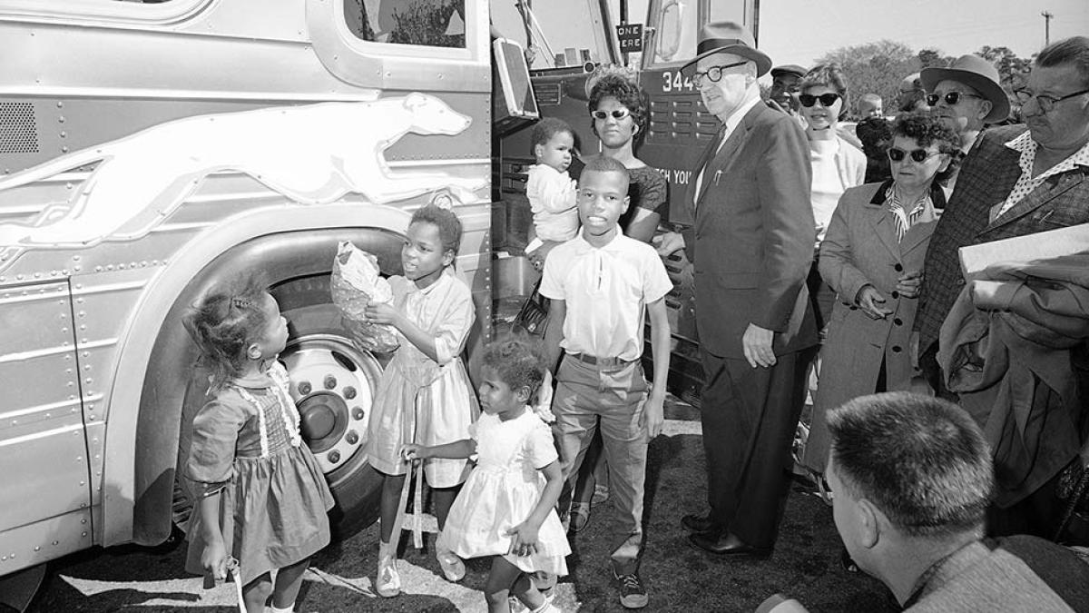 black and white photo of a family getting off a bus and being photographed by photographers
