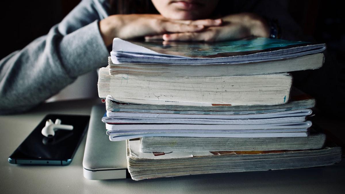 student leaning on stack of textbooks