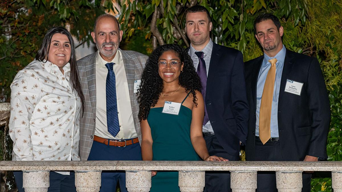 The Hall of Fame Class of 2022, two women and three men, stand on a balcony