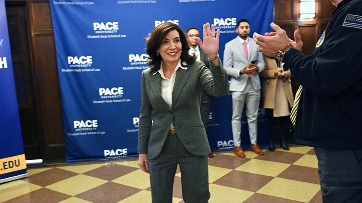 NYS Governor Kathy Hochul walking through a hallway waving to people.