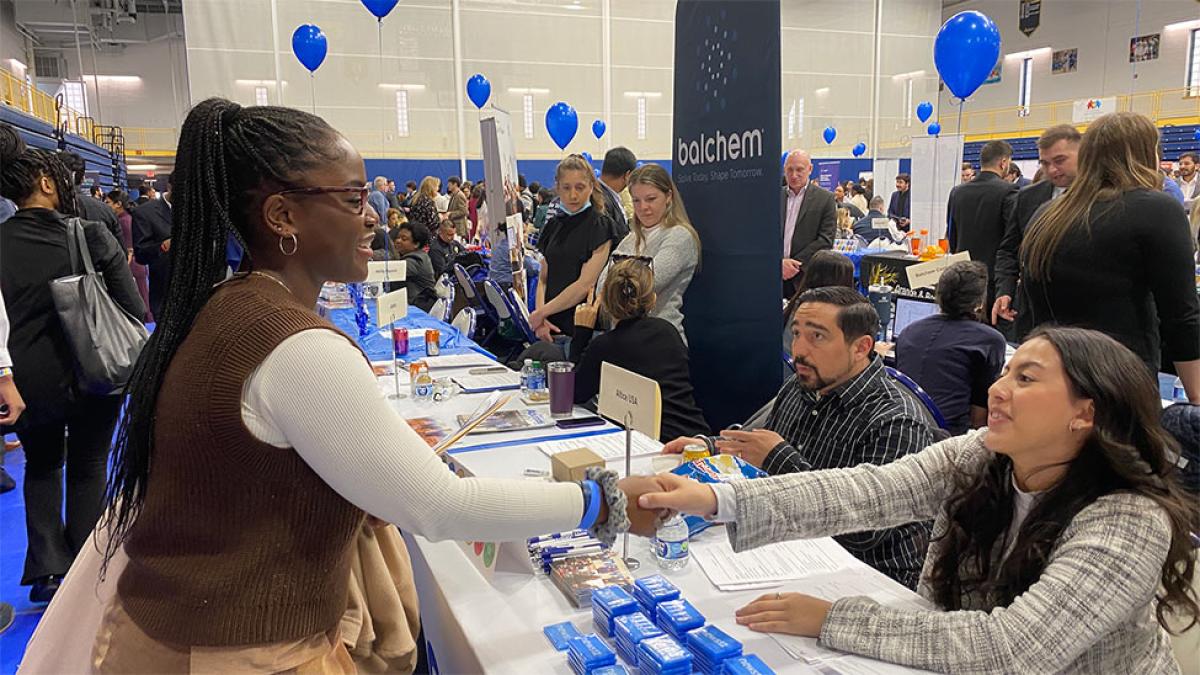 Pace University student at a job fair shaking hands with a potential employer 