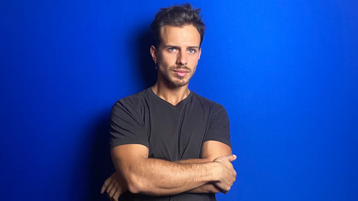 man with arms crossed in front of blue wall