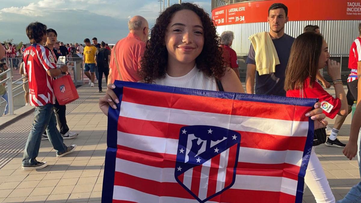 Lubin student Kelsey Tulley '25 at a stadium in Madrid holding a flag with the soccer crest of the city of Madrid