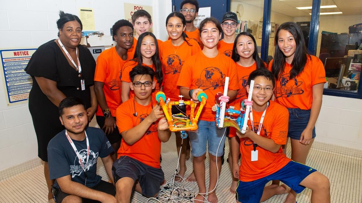 Seidenberg Professor Pauline Mosley with students from Camp Cryptobot holding robots they built with pipes