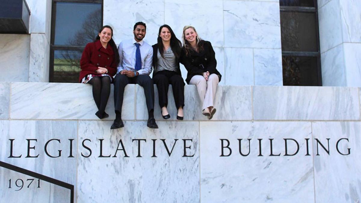 Four Pace students sitting atop the balcony of the NYS Legislative Building