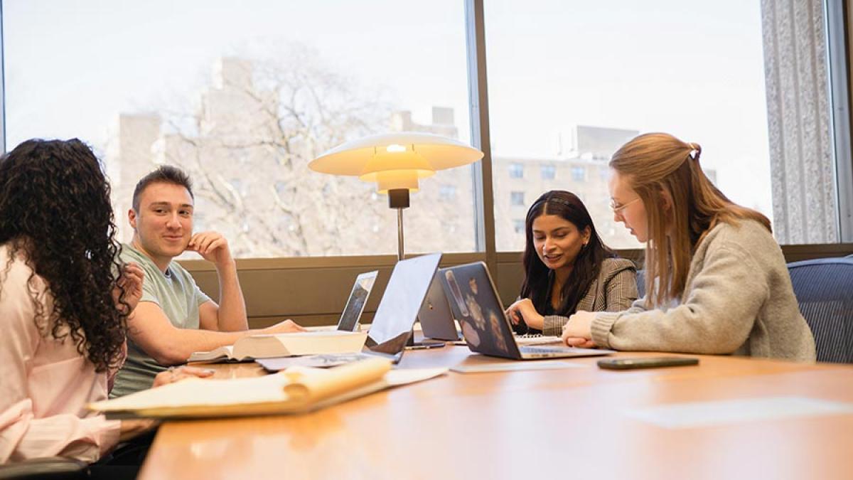 Four Elisabeth Haub School of Law students at a table studying and conversing