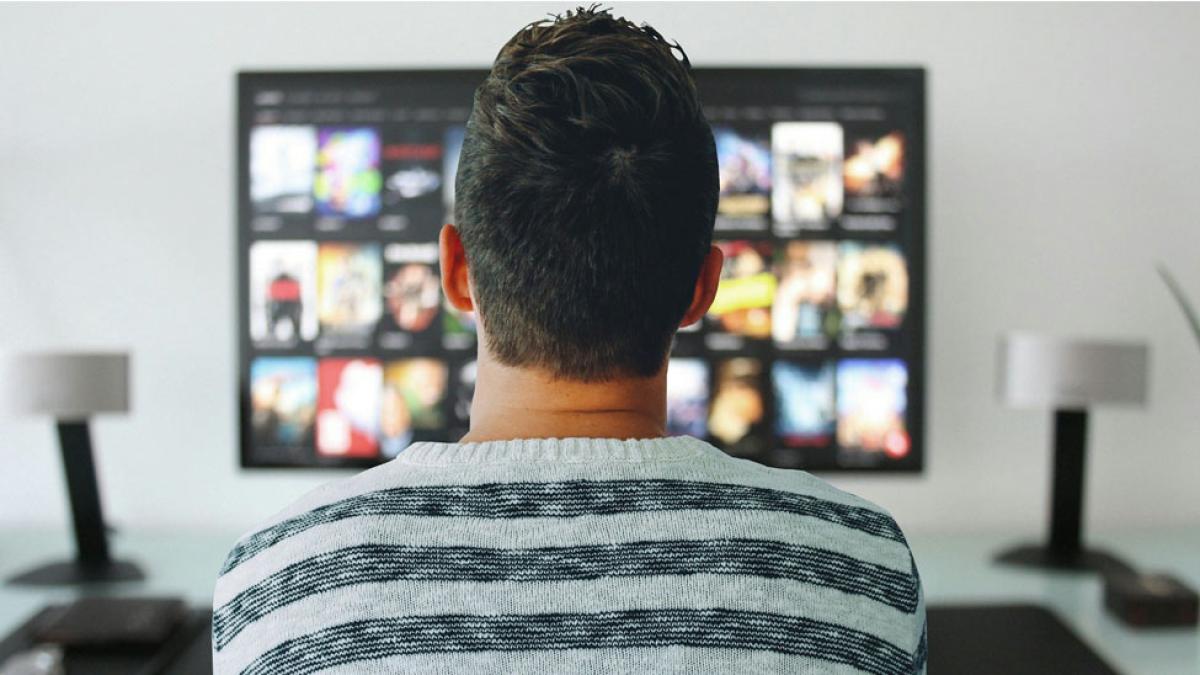 man sitting in front of a large television