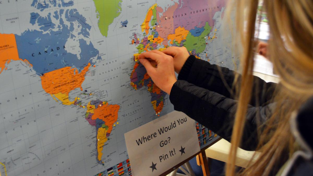 two female Pace University students adding pins to a map of the world to indicate where they would like to study at a Study Abroad Fair