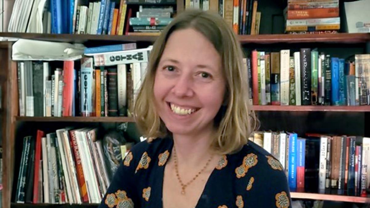 Pace University Associate Professor of English, Kelly Krietz smiling with books behind her