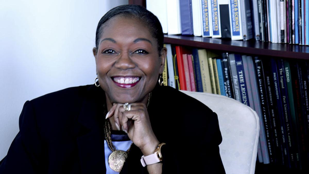 Tresmaine Grimes sitting in a chair with books on a shelf behind her