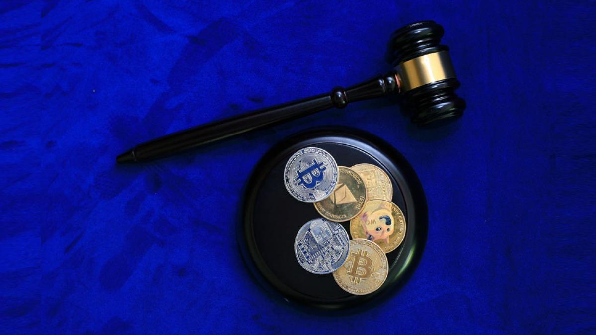 judge's gavel and sound block with Binance and other cryptocoins embedded in the block